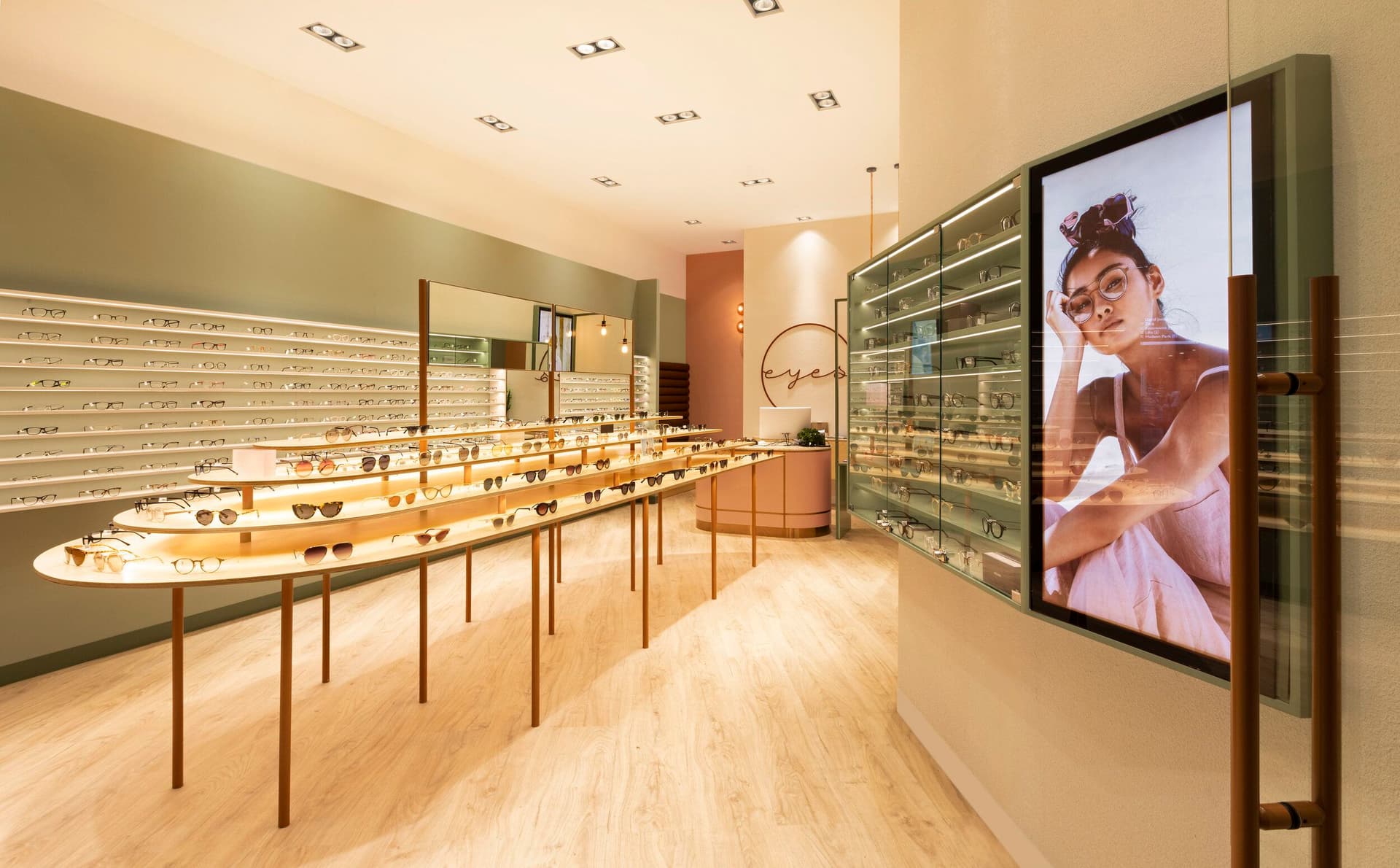 Interior of an M Optic store with eyeglasses and sunglasses displayed on lit shelves and tables